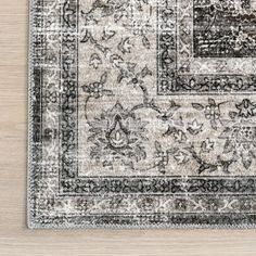 an area rug on a wooden floor with white and black accents, including a floral design