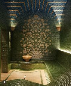 an artisticly designed room with green tiles and a bowl on the floor in front of it