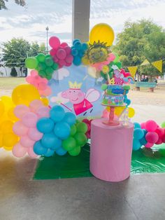 a birthday cake and balloons are on display at the entrance to an outdoor party venue