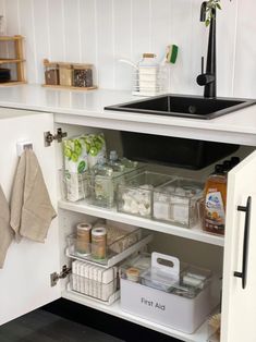 an organized kitchen with white cabinets and black counter tops is pictured in this image, there are various items on the shelves