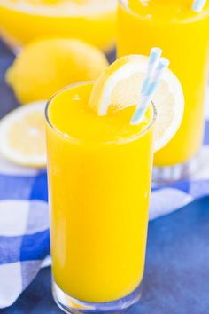 a glass filled with orange juice on top of a blue and white checkered table cloth