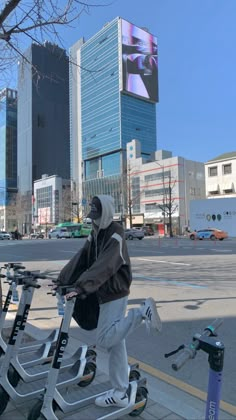 a man is riding an electric scooter on the sidewalk in front of some tall buildings