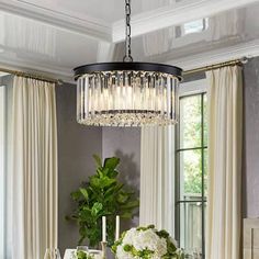 a dining room table set for two with flowers and candles on it, along with an elegant chandelier hanging from the ceiling