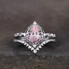 an engagement ring with a pink stone in the center and white diamonds on each side