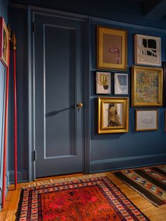 a room with blue walls and pictures on the wall, rugs and framed photos