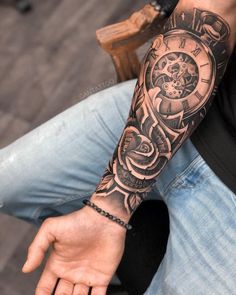 a man's arm with a clock tattoo on it and his hand in the air