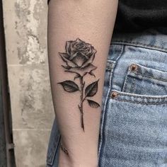 a woman's arm with a rose tattoo on the left side of her arm