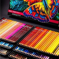 an assortment of colored pencils in tins on a black surface with the box full of them