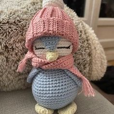 a crocheted penguin with a pink hat and scarf sitting next to a stuffed animal