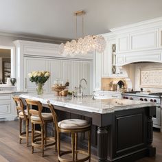 a large kitchen with white cabinets and marble counter tops, an island in the middle