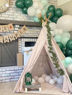 a teepee tent is set up in front of balloons and garlands for a birthday party