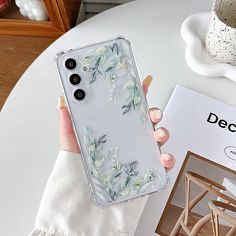 a woman is holding up her phone case with flowers on the front and back cover