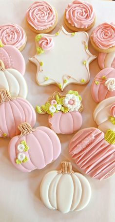 some decorated cookies are sitting on a white tablecloth with flowers and pumpkins in the background