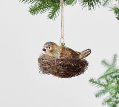 an ornament shaped like a bird in a nest hanging from a christmas tree