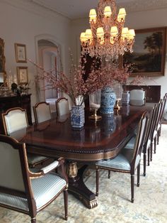 a dining room table with blue and white vases on it's centerpiece