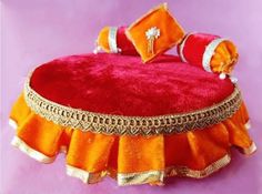 an orange and red cushion sitting on top of a purple surface with gold trimmings