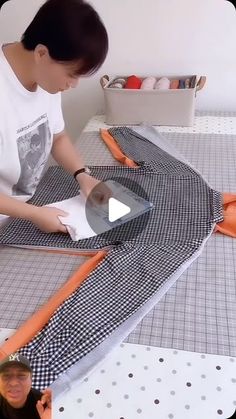 a woman is cutting fabric on the table