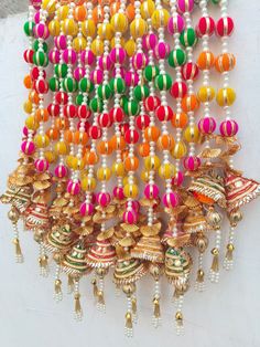 multicolored beaded necklaces hanging from the side on a white wall in india