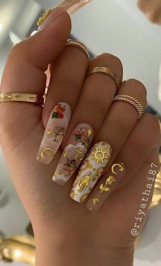 a woman's hand with gold and white nail polishes on her nails, including rings