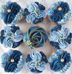 cupcakes decorated with blue frosting and gold decorations on a white marble surface