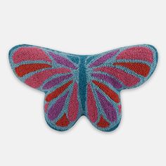 a pink and blue butterfly shaped pillow on a white background