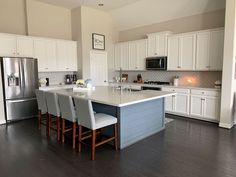 a large kitchen with white cabinets and gray counter tops, along with an island in the middle