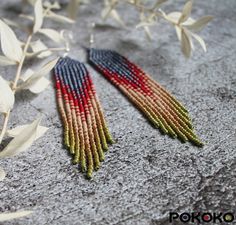 red, white and blue seed beaded earrings with leaves on the ground next to it