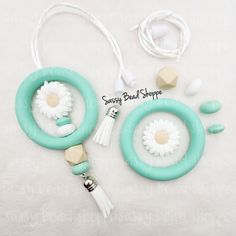 two necklaces with flowers and tassels attached to them on a white background