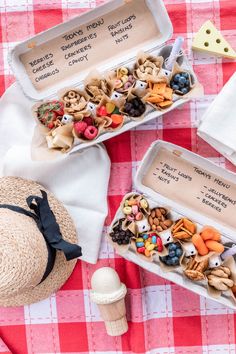 two boxes filled with different types of food on top of a red and white checkered table