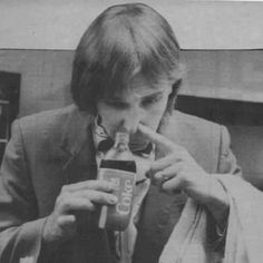 an old black and white photo of a man holding a cell phone to his mouth