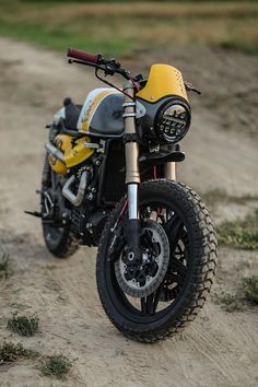 a yellow and black motorcycle parked on top of a dirt road