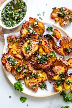 grilled potatoes with herbs on a plate next to a small bowl of pesto