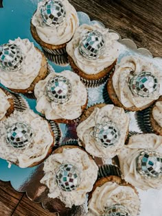 several cupcakes with white frosting and silver decorations on a blue platter