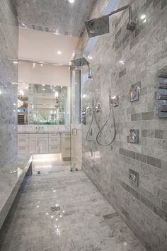 a large bathroom with marble tile walls and flooring, along with a walk in shower