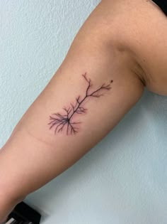 a woman's arm with a small branch tattoo on the left side of her arm