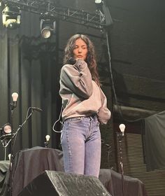 a woman standing on top of a stage with headphones in her ears and microphone to her ear