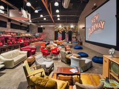 a large room with lots of chairs and couches on the floor in front of a projector screen