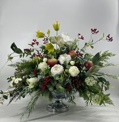 a vase filled with flowers and greenery on top of a white tablecloth covered floor