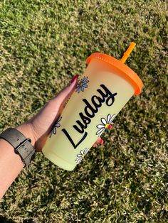 a person holding up a yellow cup with the word lady on it and an orange lid