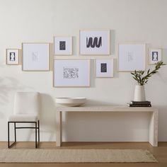 a white table and some chairs in a room with pictures on the wall above it