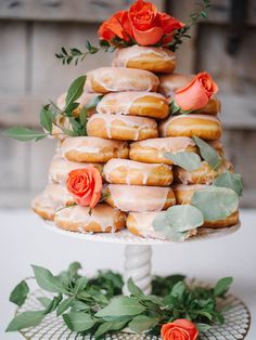 there are donuts stacked on top of each other with flowers in the middle and greenery around them