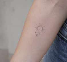 a small sun and arrow tattoo on the arm