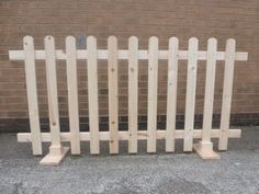 a wooden fence is standing in front of a brick wall and cement flooring area