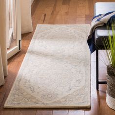 a living room area with a rug, chair and potted plant on the floor