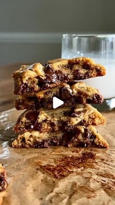 three chocolate chip cookies stacked on top of each other next to a glass of milk