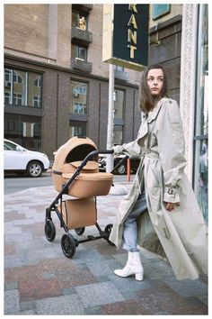 a woman walking down the street with a baby stroller in front of her,