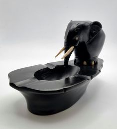 an elephant sculpture sitting on top of a black bowl