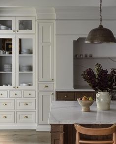 a kitchen with white cabinets and marble counter tops