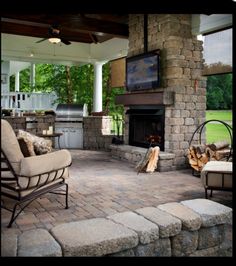 an outdoor living area with fireplace, chairs and television on top of the fire place