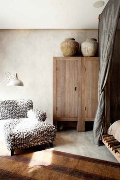 a living room filled with furniture and a wooden cabinet next to a window covered in curtains